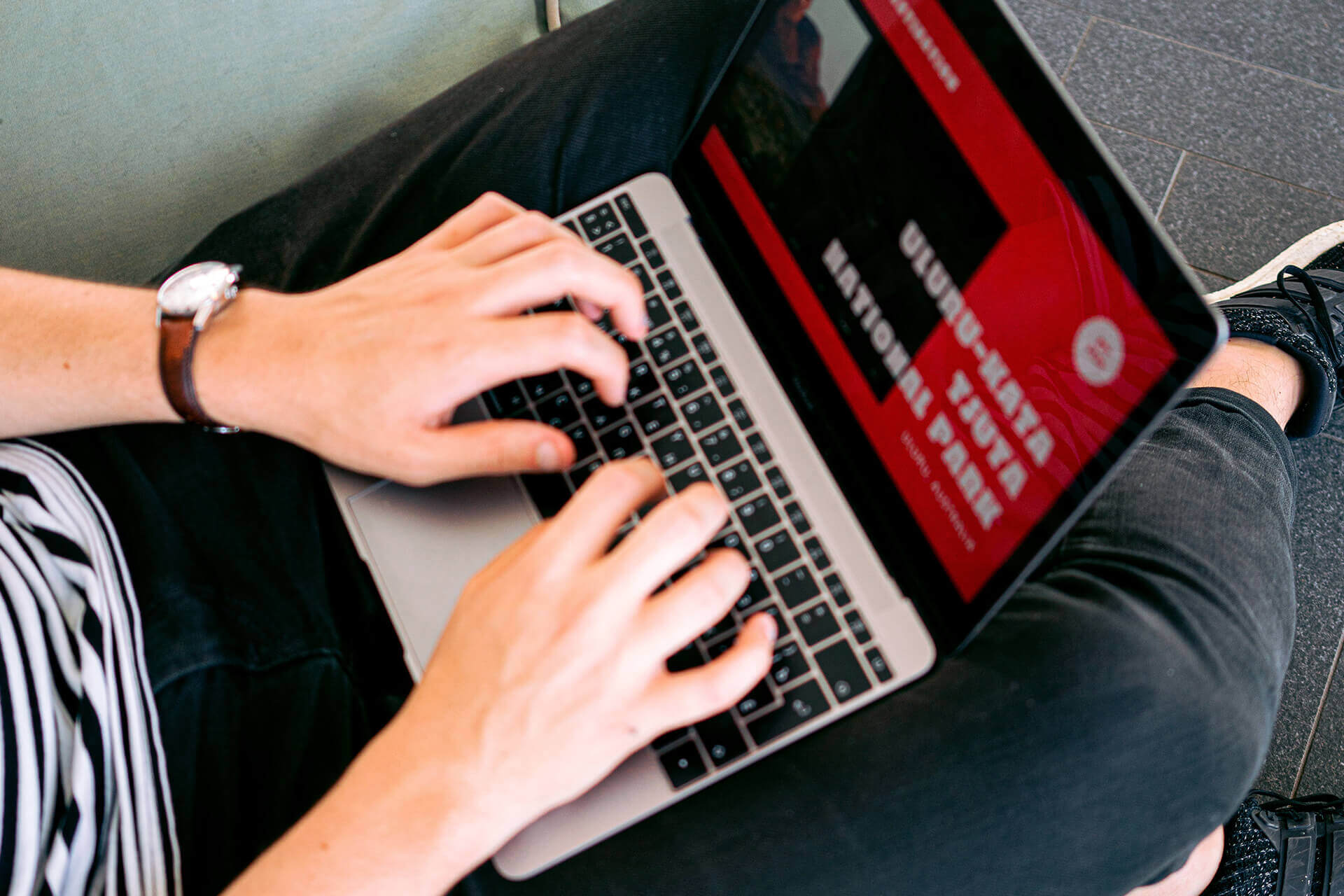 Hands typing on a laptop resting on a lap